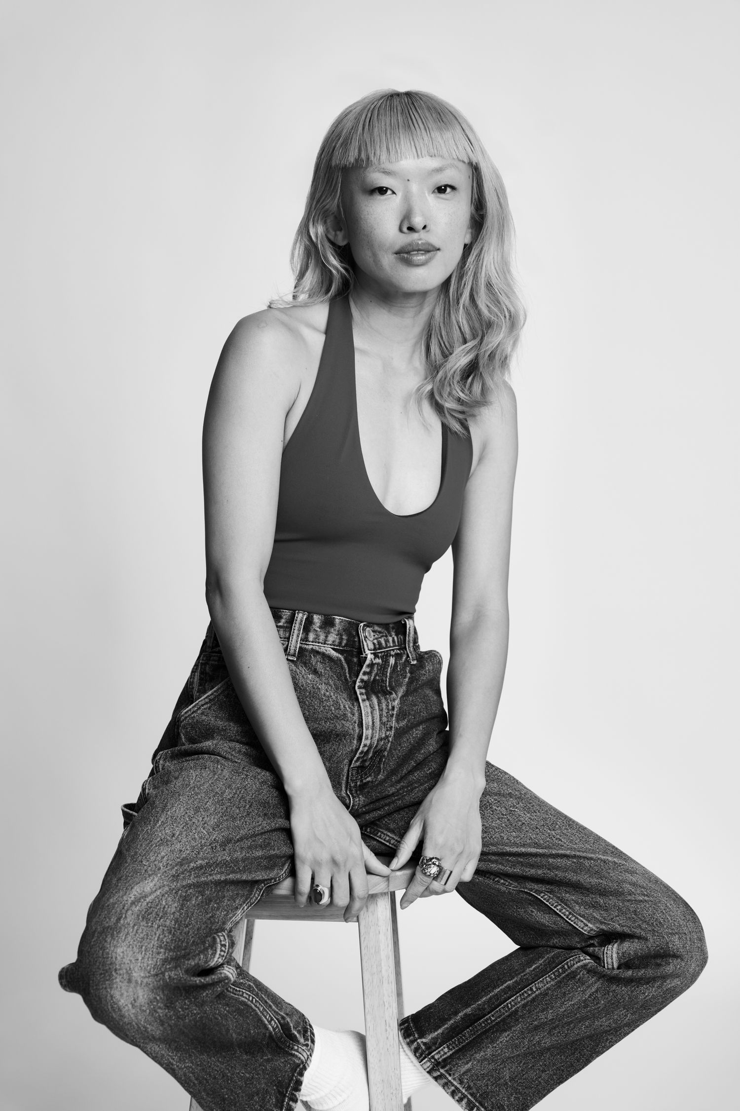 Black and white portrait series featuring model in tank top and wide-leg jeans.