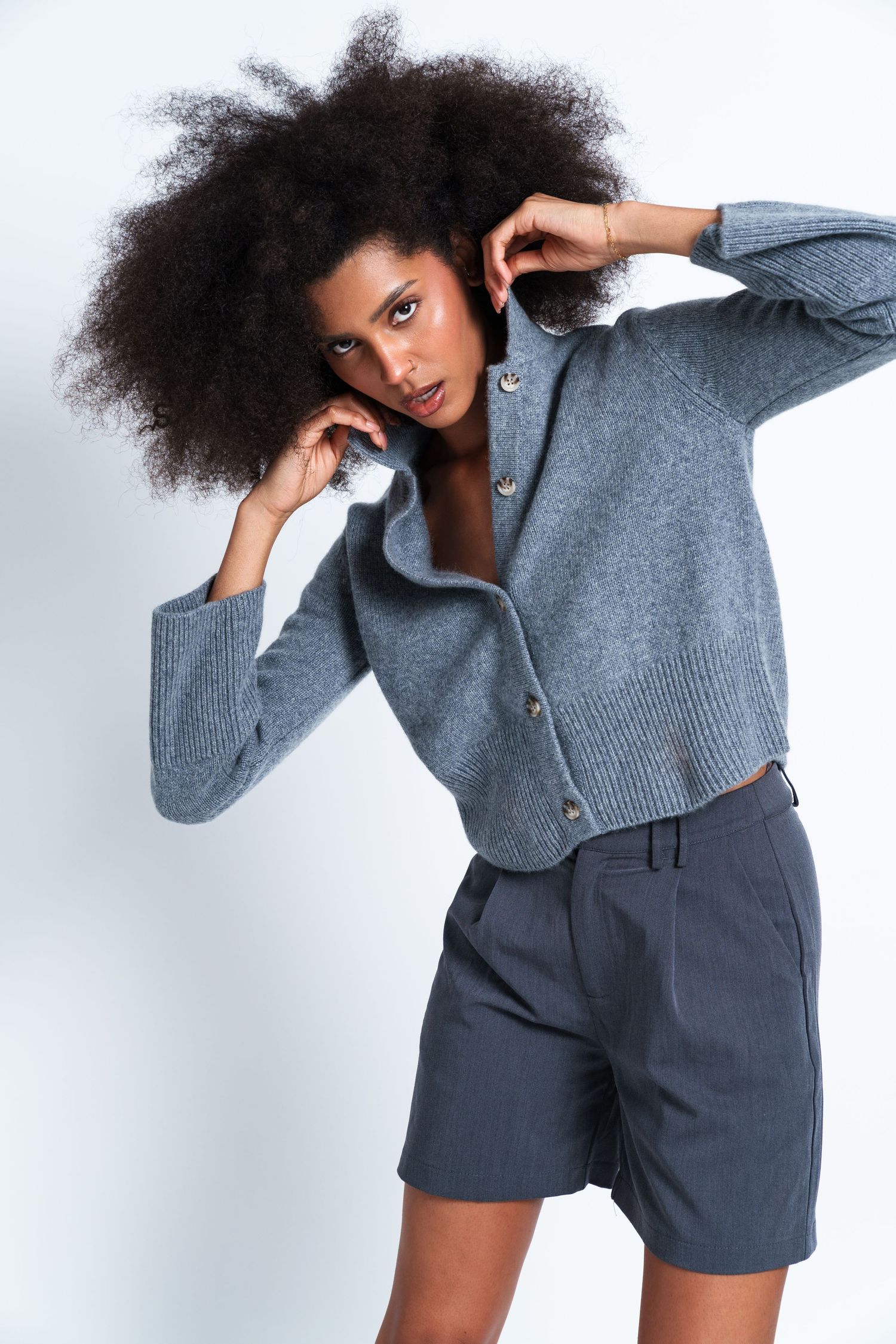 Fashion series showing gray knit sweater and shorts combination in studio setting.