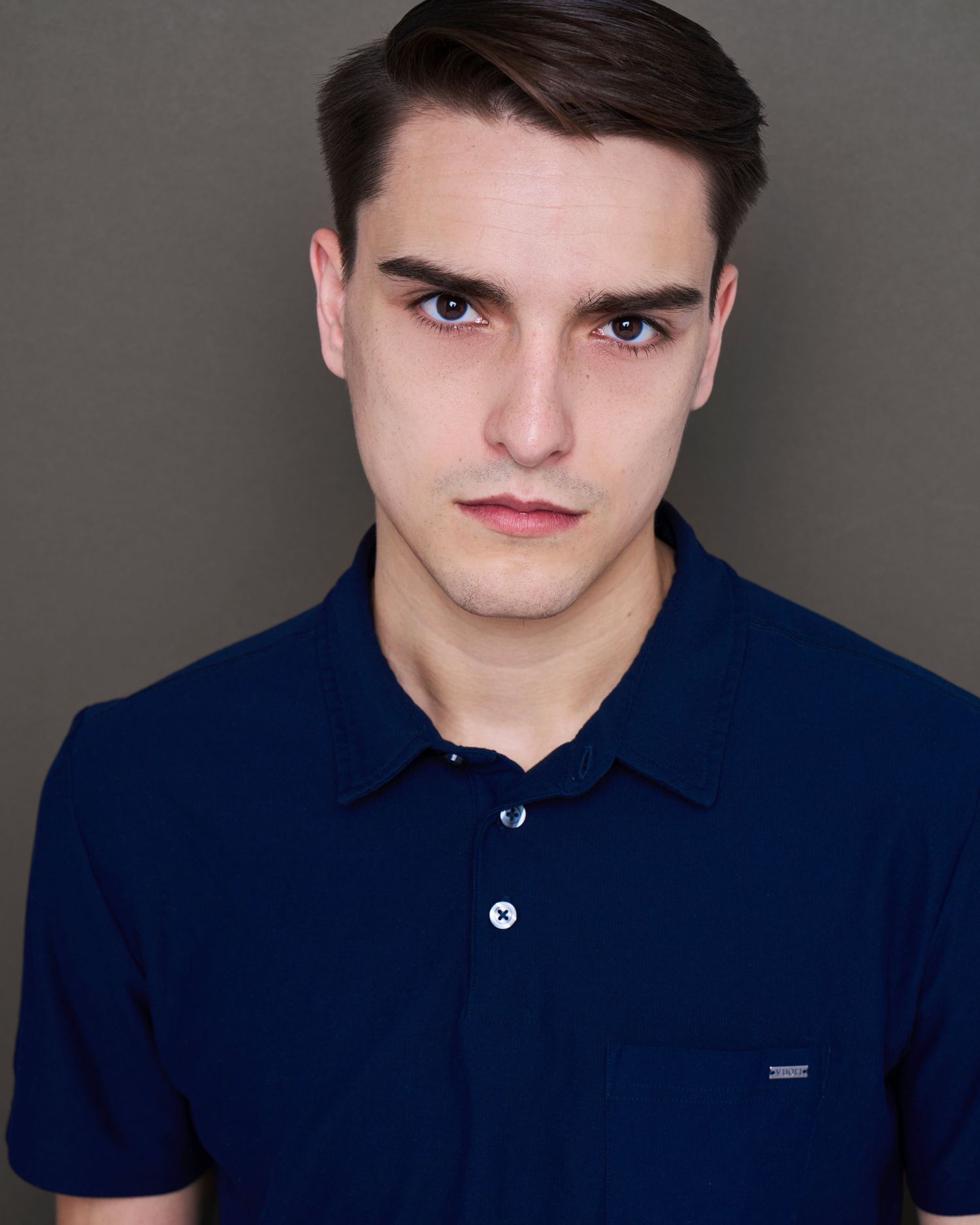 Professional headshot series showing different expressions while wearing a navy blue polo shirt against grey background.