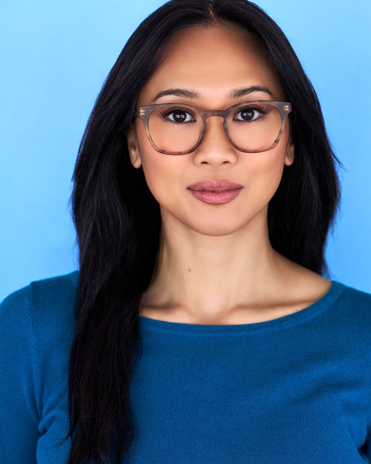 Professional headshots in blue top against light blue background wearing glasses.