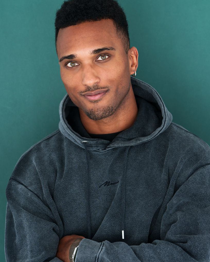 Casual portraits in dark grey hoodie against teal studio background.