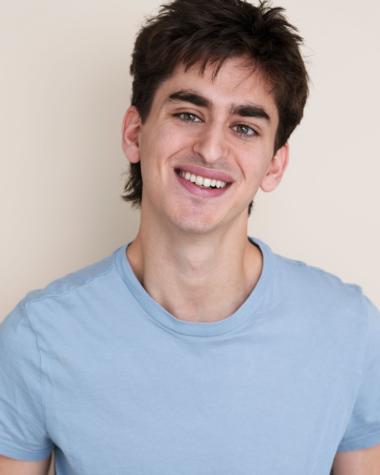 Cheerful portrait series wearing a light blue t-shirt against white background.