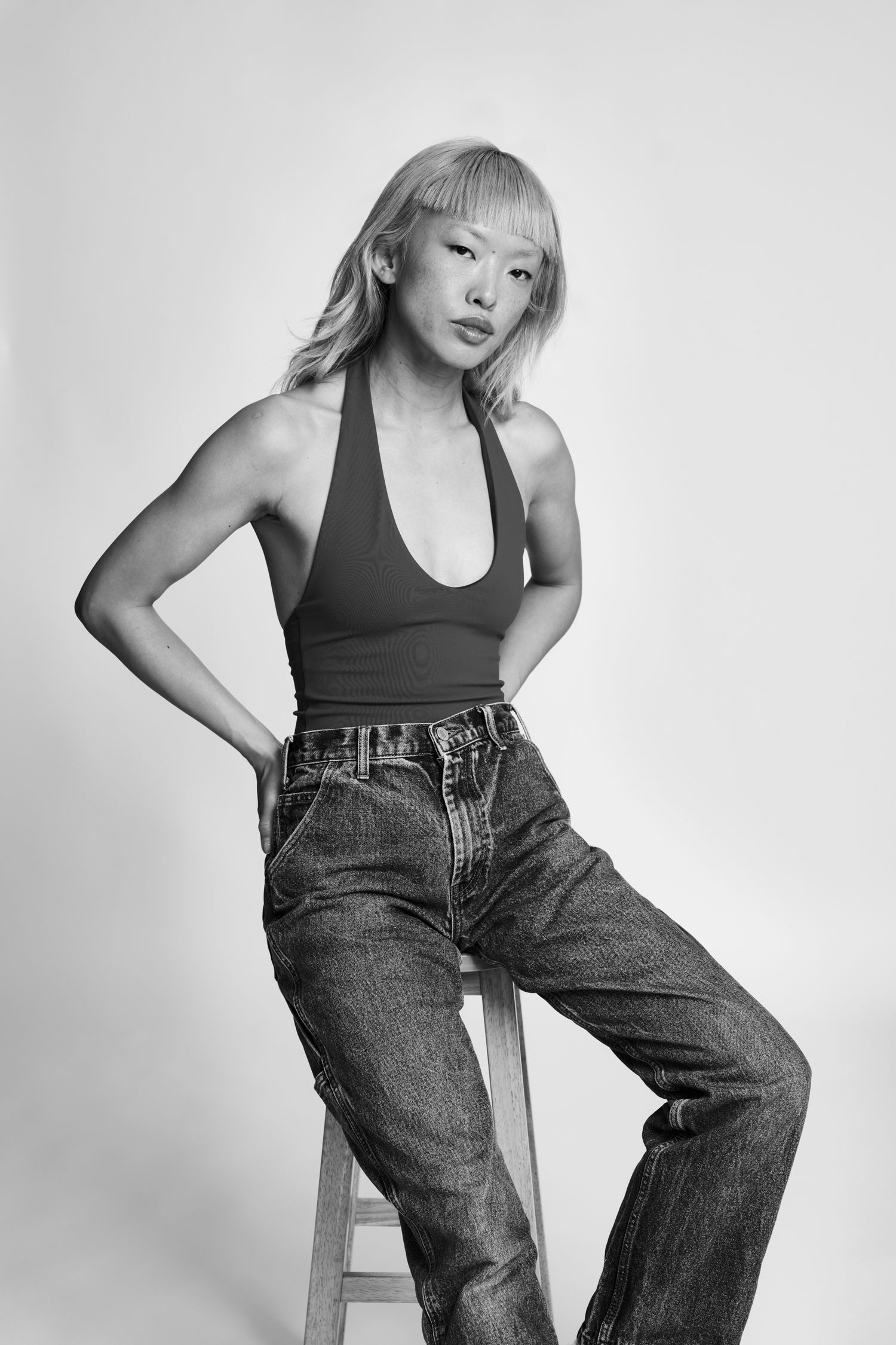 Fashion editorial in black and white showing urban casual wear with denim and tank top.