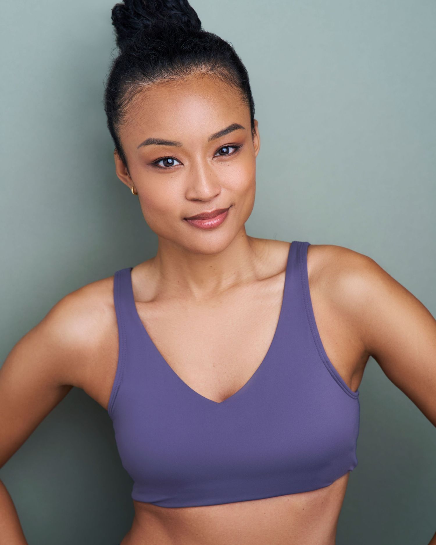 Athletic portrait of a person in purple sports bra against grey background.