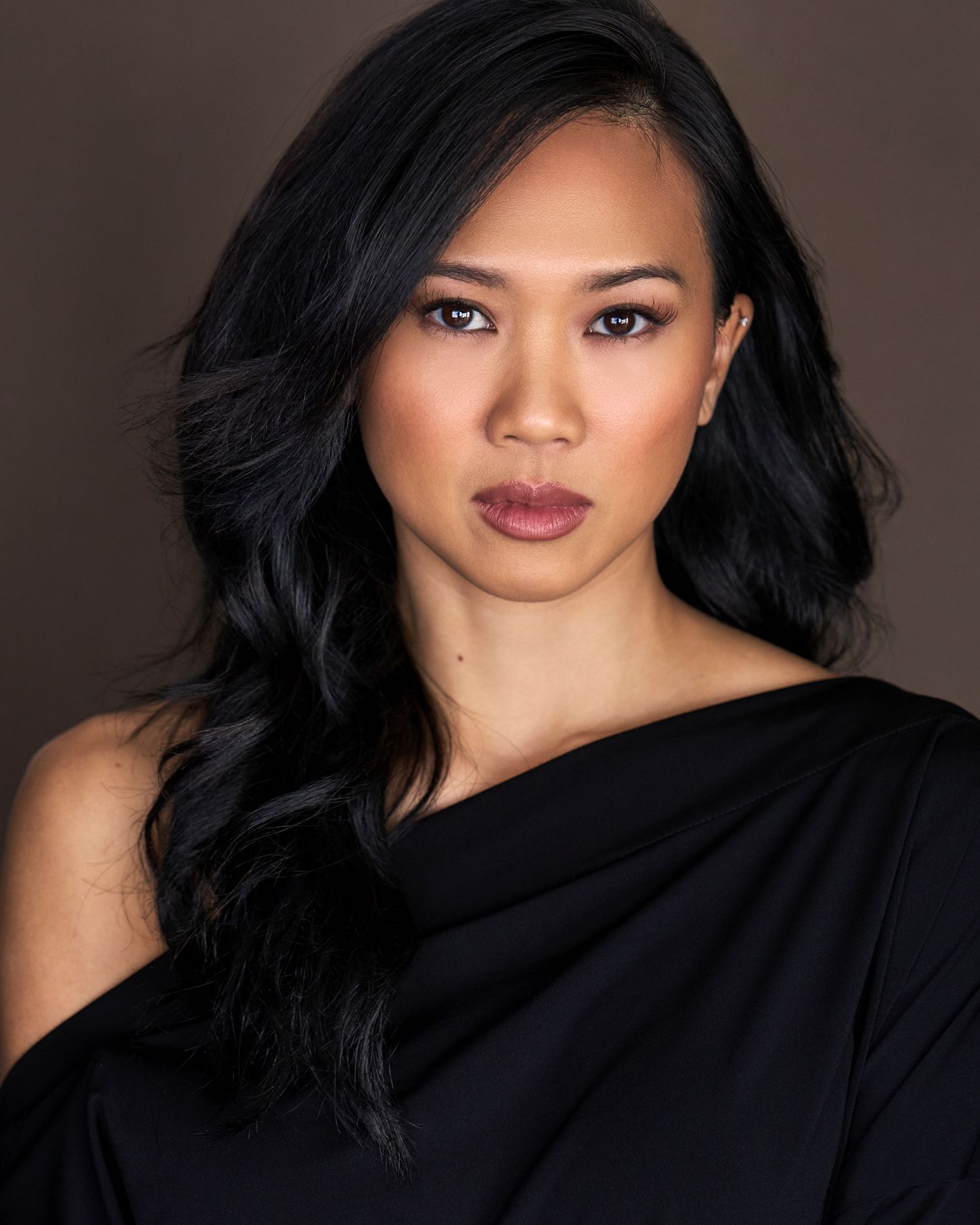 Dramatic portrait series in black outfit against dark background with moody lighting.