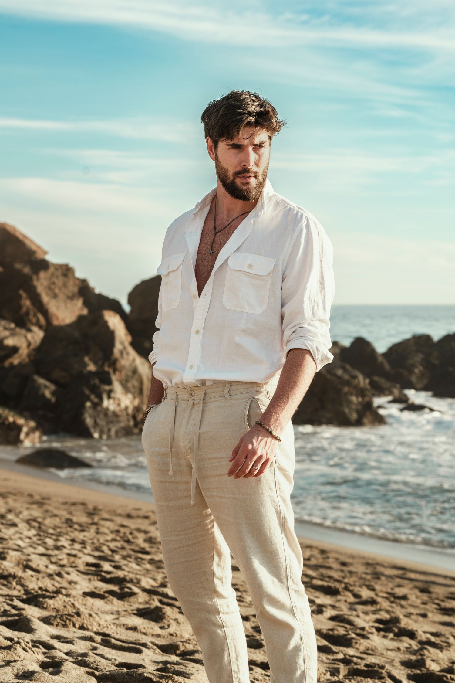 Fashion shoot featuring white summer outfit against coastal beach backdrop.