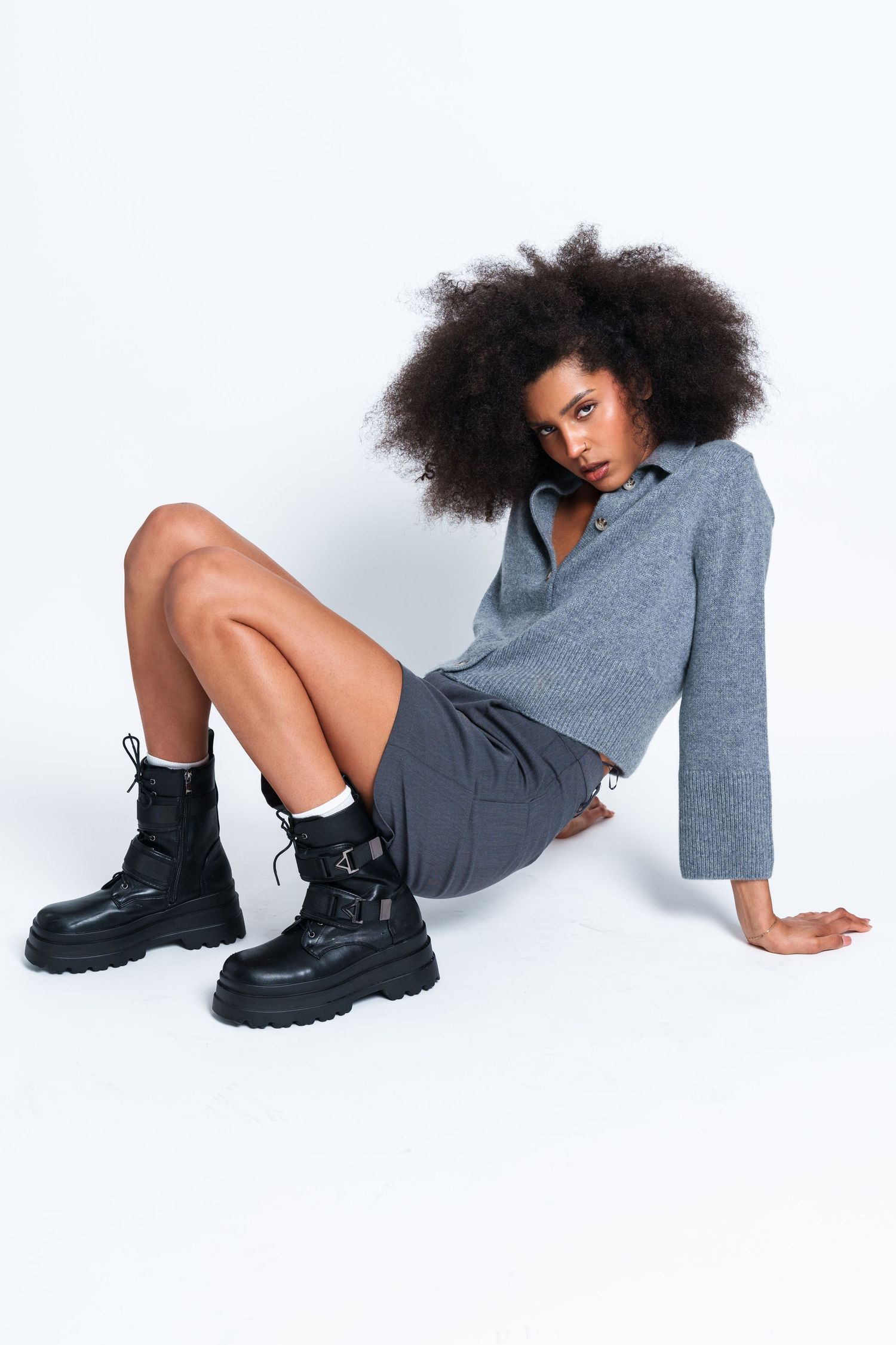 Artistic fashion poses featuring gray knitwear and black combat boots on white backdrop.
