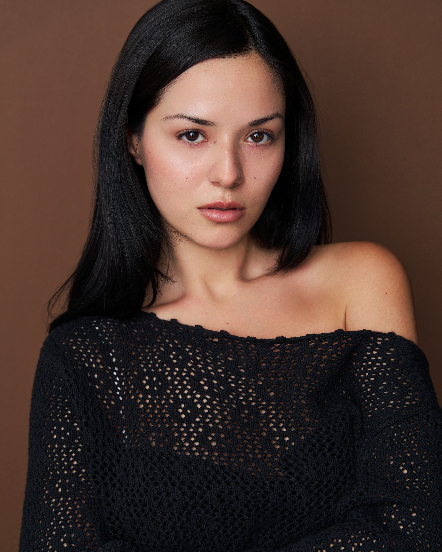 Portrait series of someone wearing a black knit sweater against a brown backdrop.