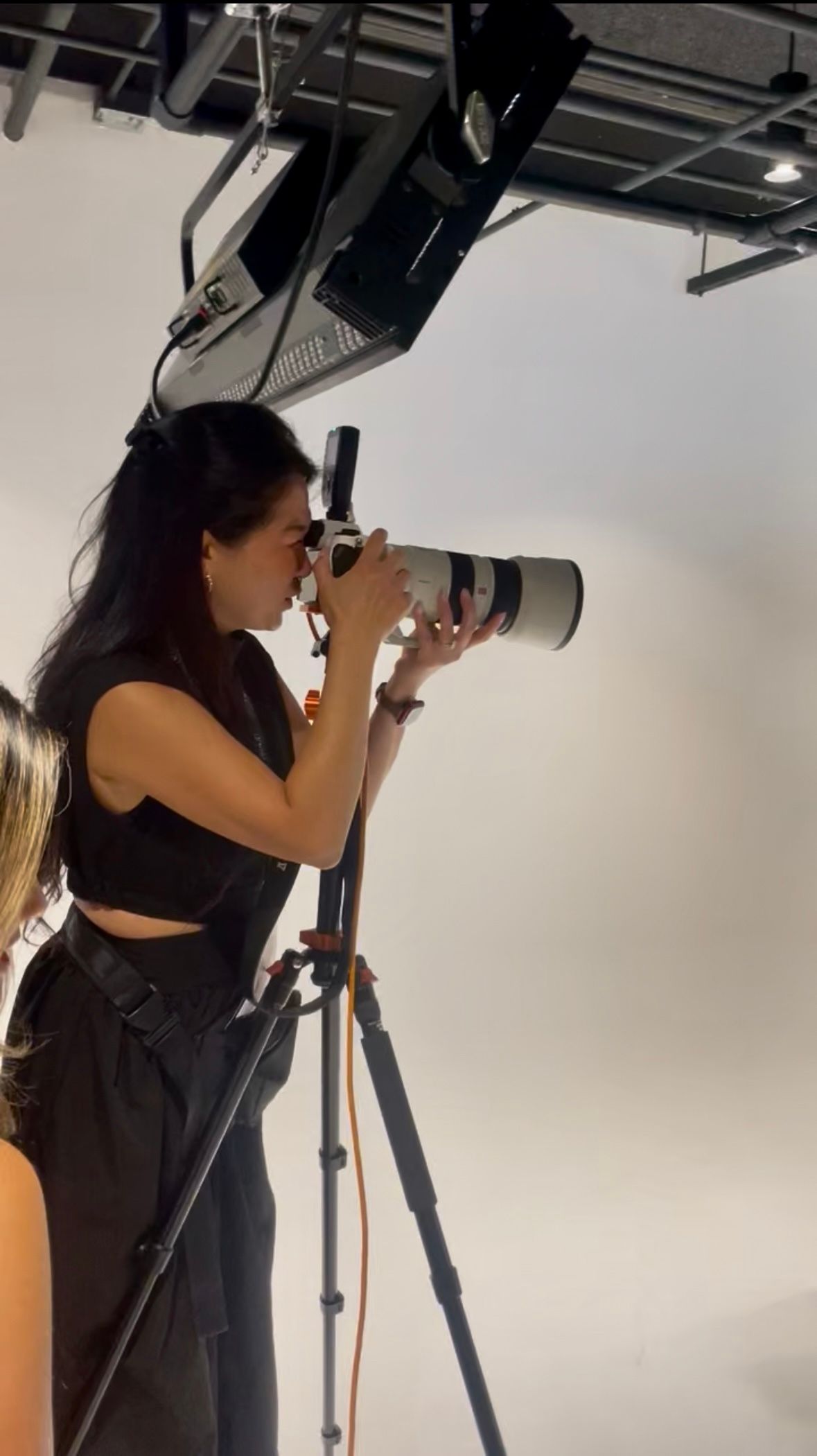 Behind the scenes photo of a photographer working with professional lighting equipment in a studio.
