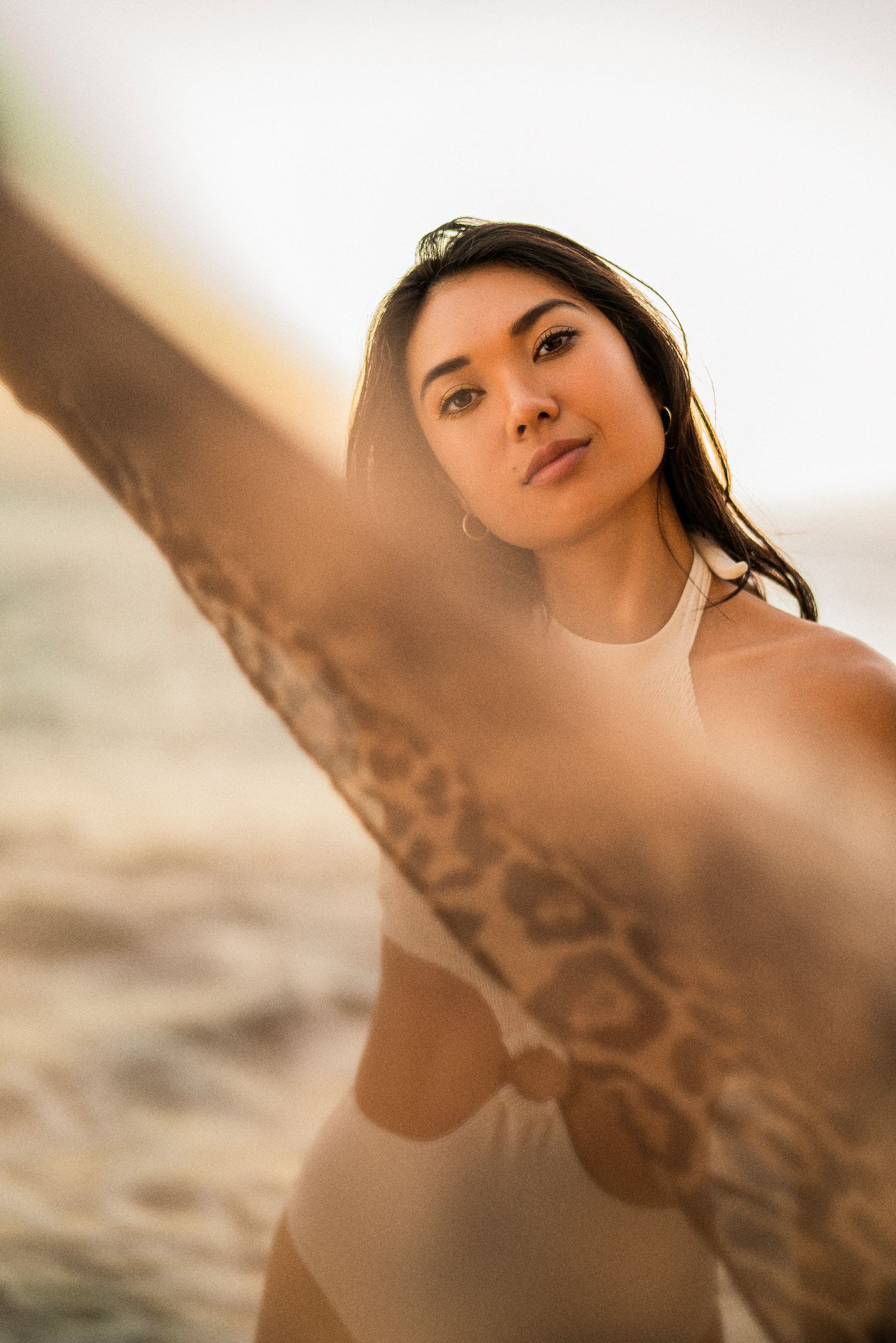 Beach fashion shoot with model holding flowing fabric at sunset.