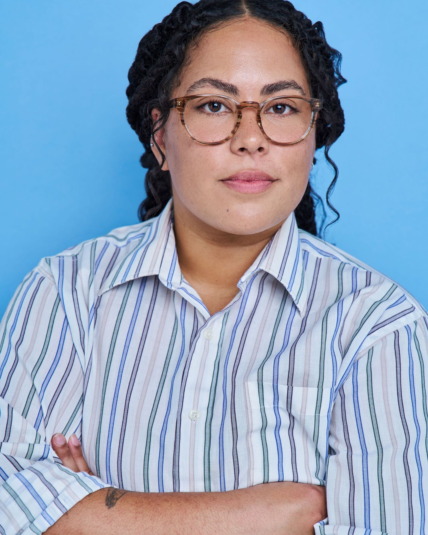 Professional portrait series in striped button-down shirt against blue backdrop.