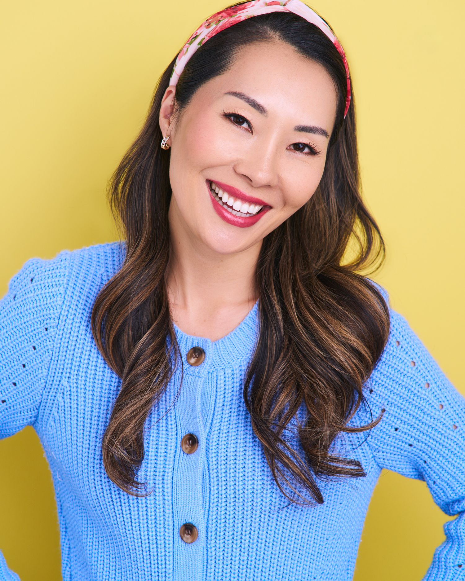 Casual portrait series in blue knit sweater and floral headband against yellow background.