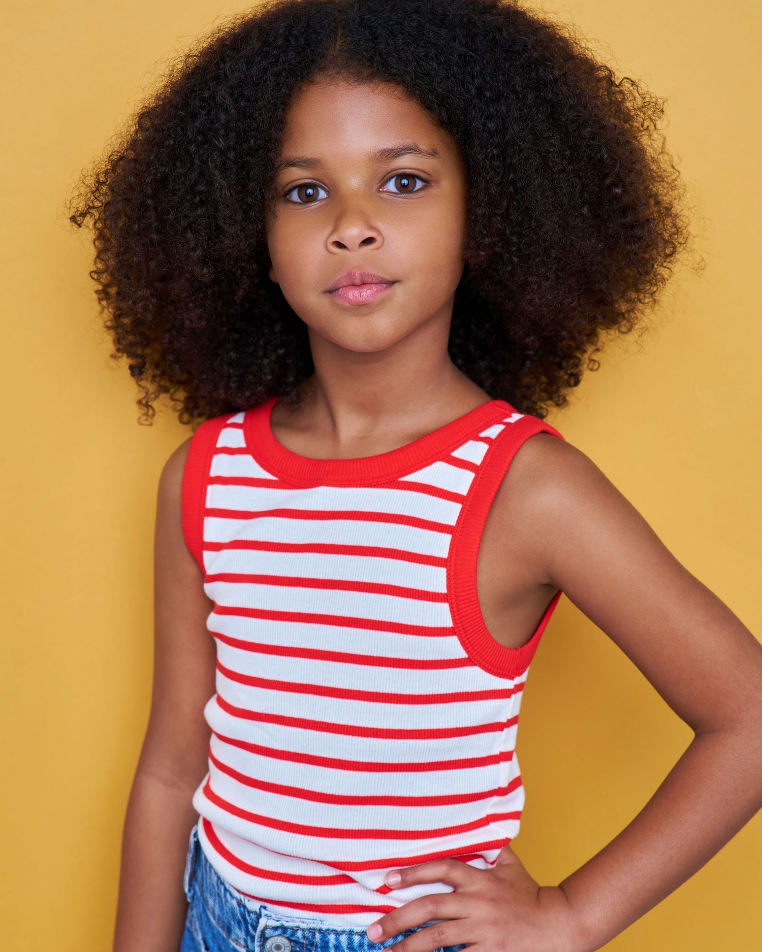 Young portrait in red and white striped tank top against yellow background.