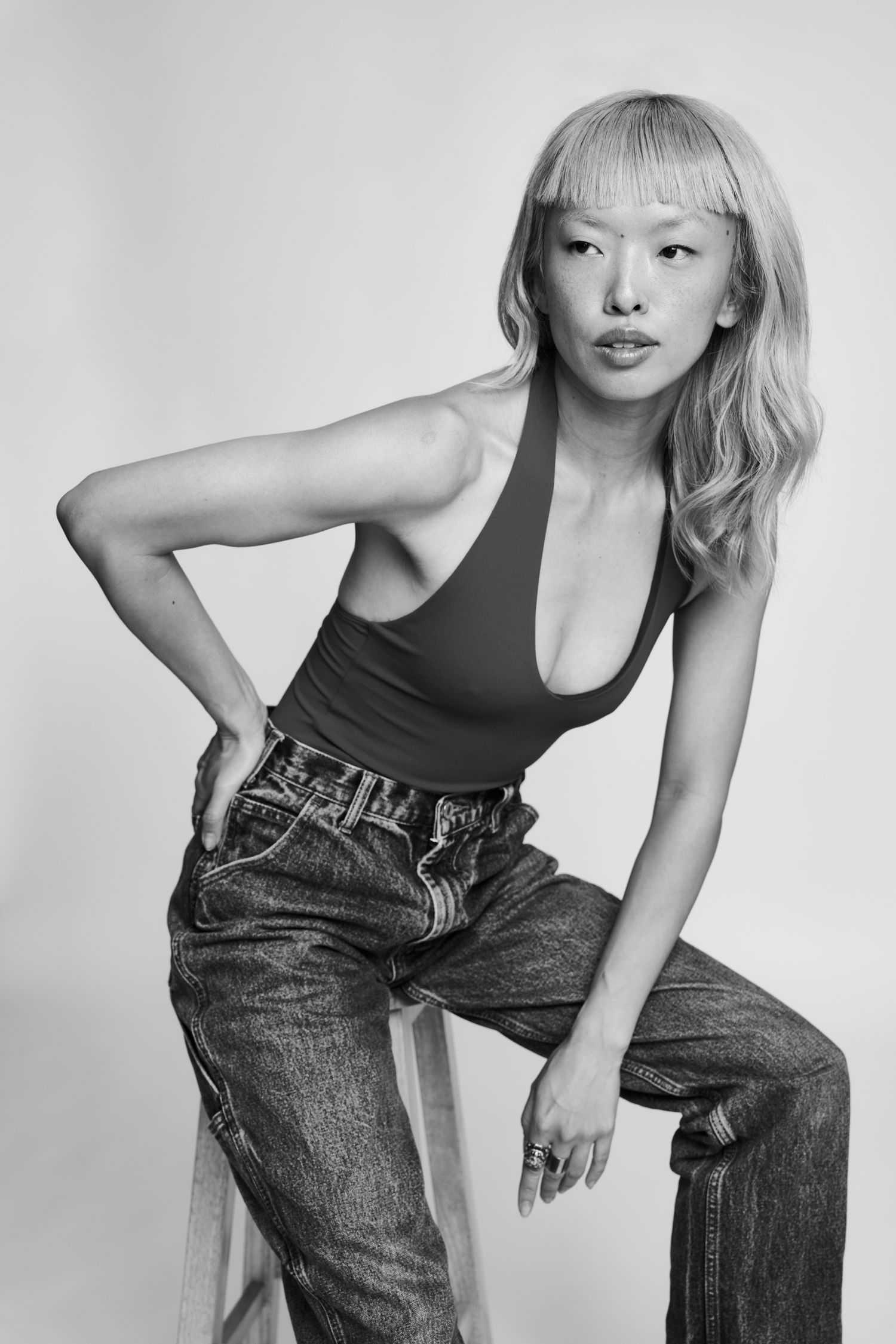 Monochrome studio portrait showing casual style with jeans and sleeveless top in dynamic poses.