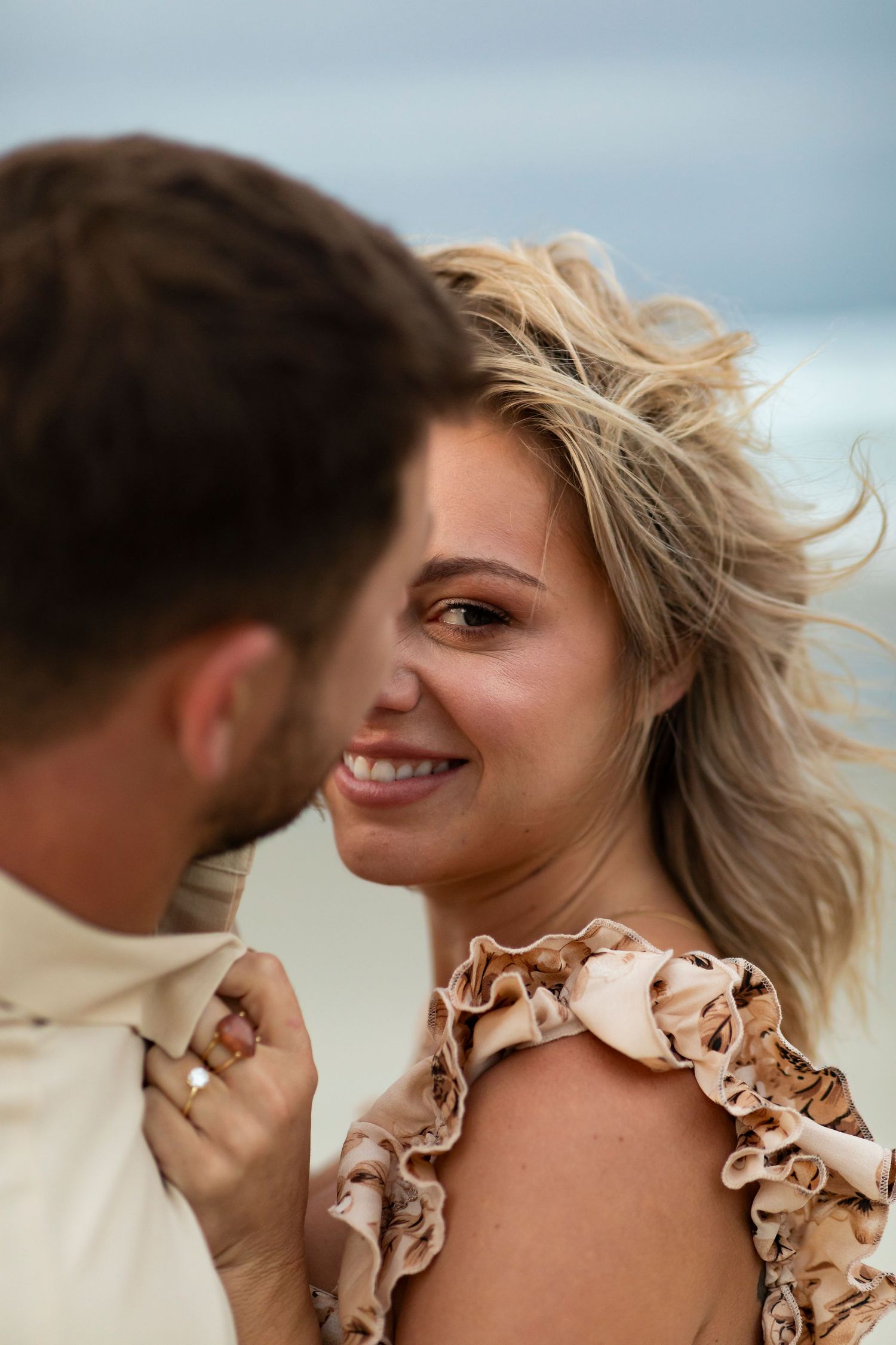 Close-up beach portrait with windswept hair and natural coastal lighting.