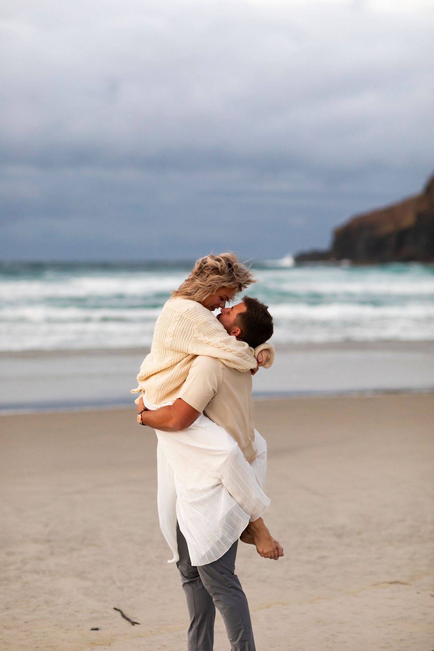 destination photo of couple on beach in New Zealand embracing