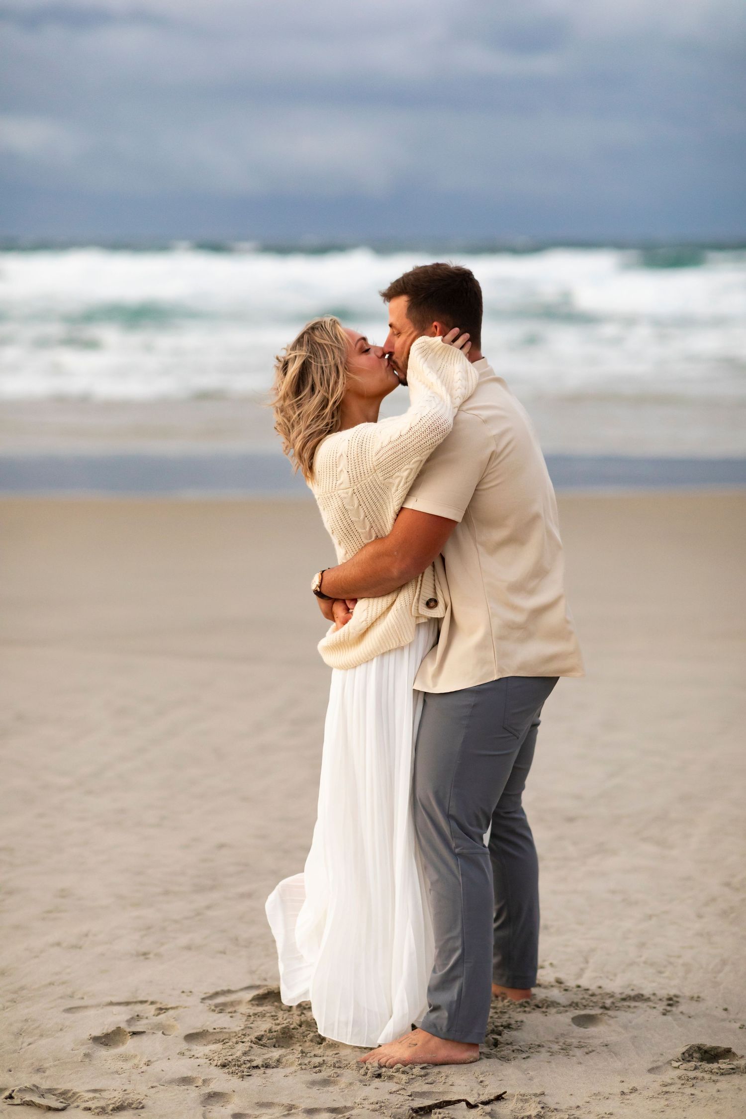 vacation photo of couple on beach in New Zealand kissing face