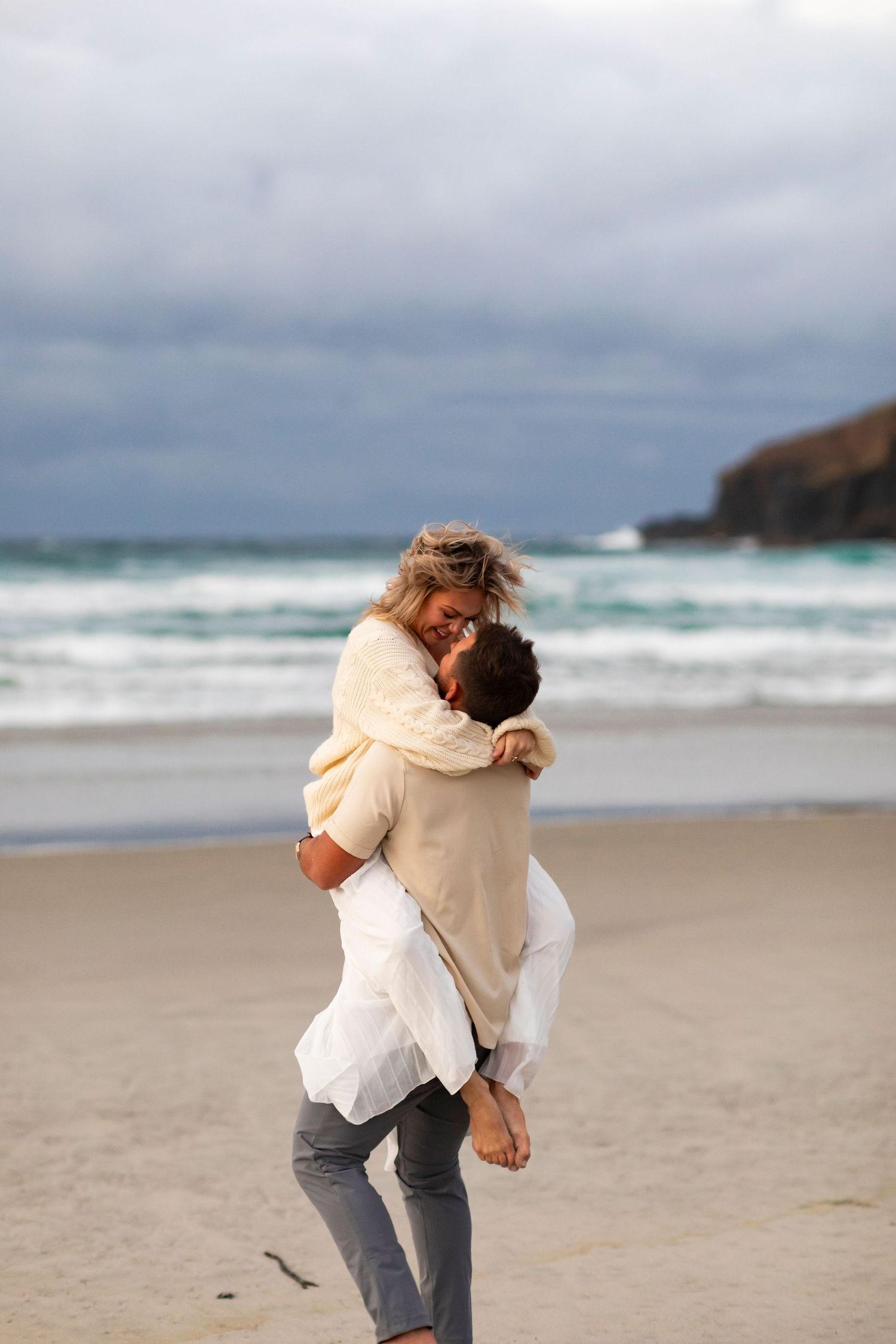 destination photo of couple on beach in New Zealand kissing