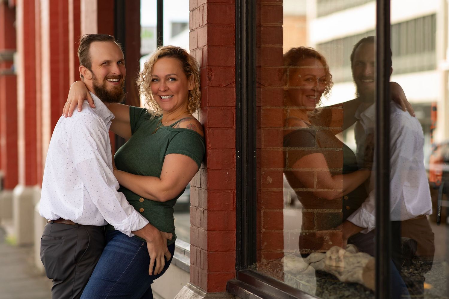 A couple practices ballroom dance moves in a studio with brick walls and mirrors.