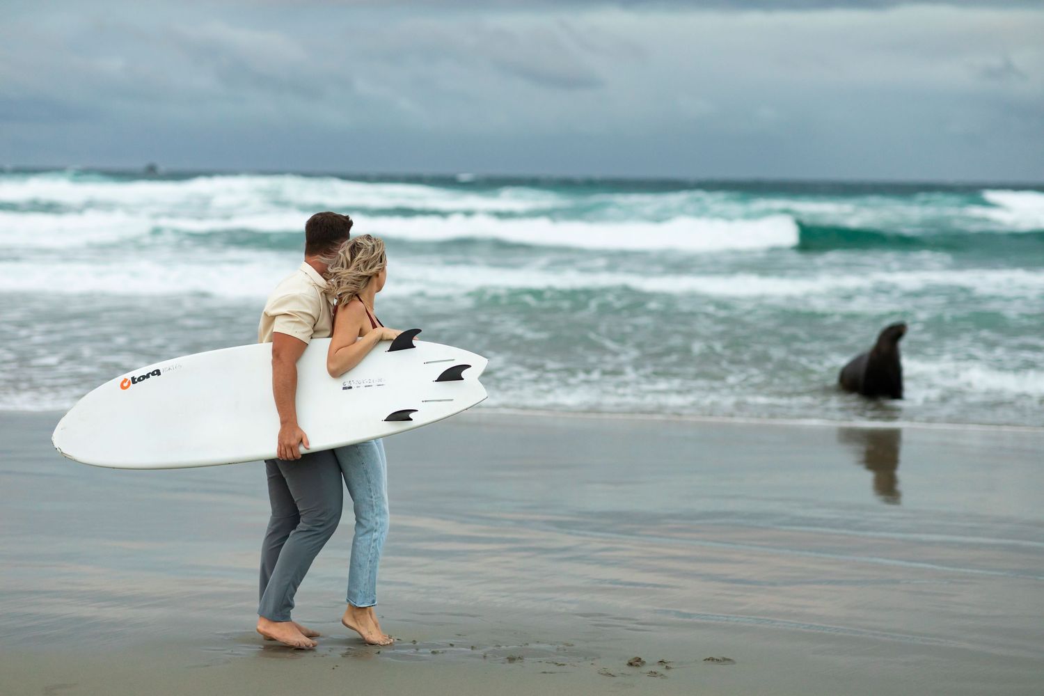 destination photoshoot of beach engagement new zealand couple surfboard meets sealion