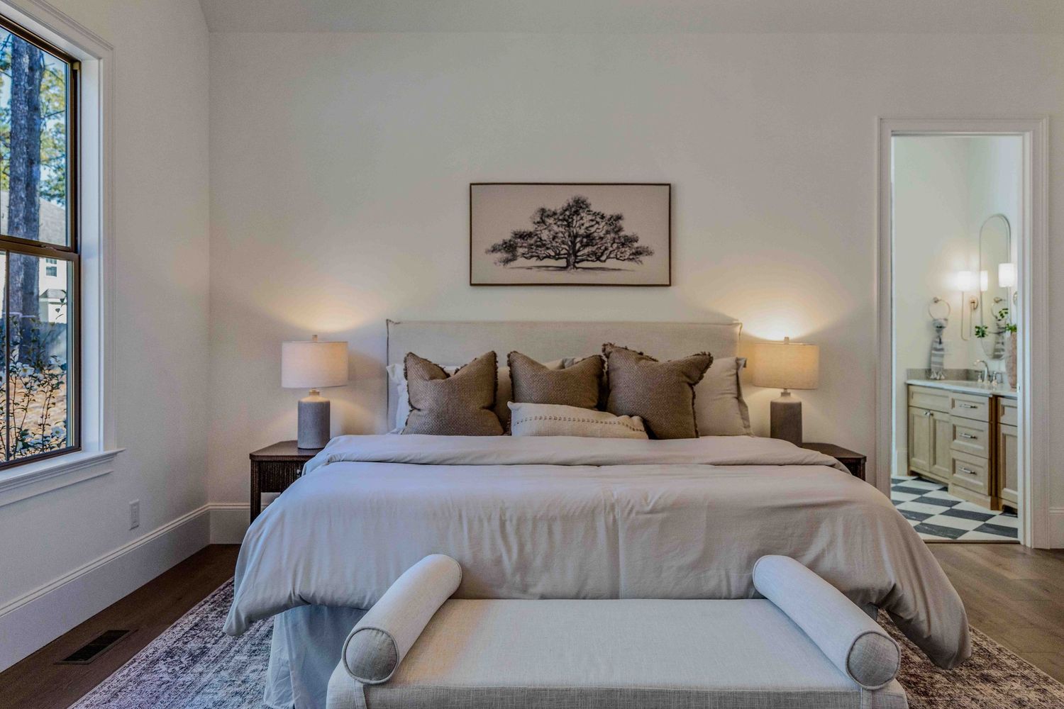 Elegant white bedroom interior with modern decor, wall art, and natural lighting through large windows.
