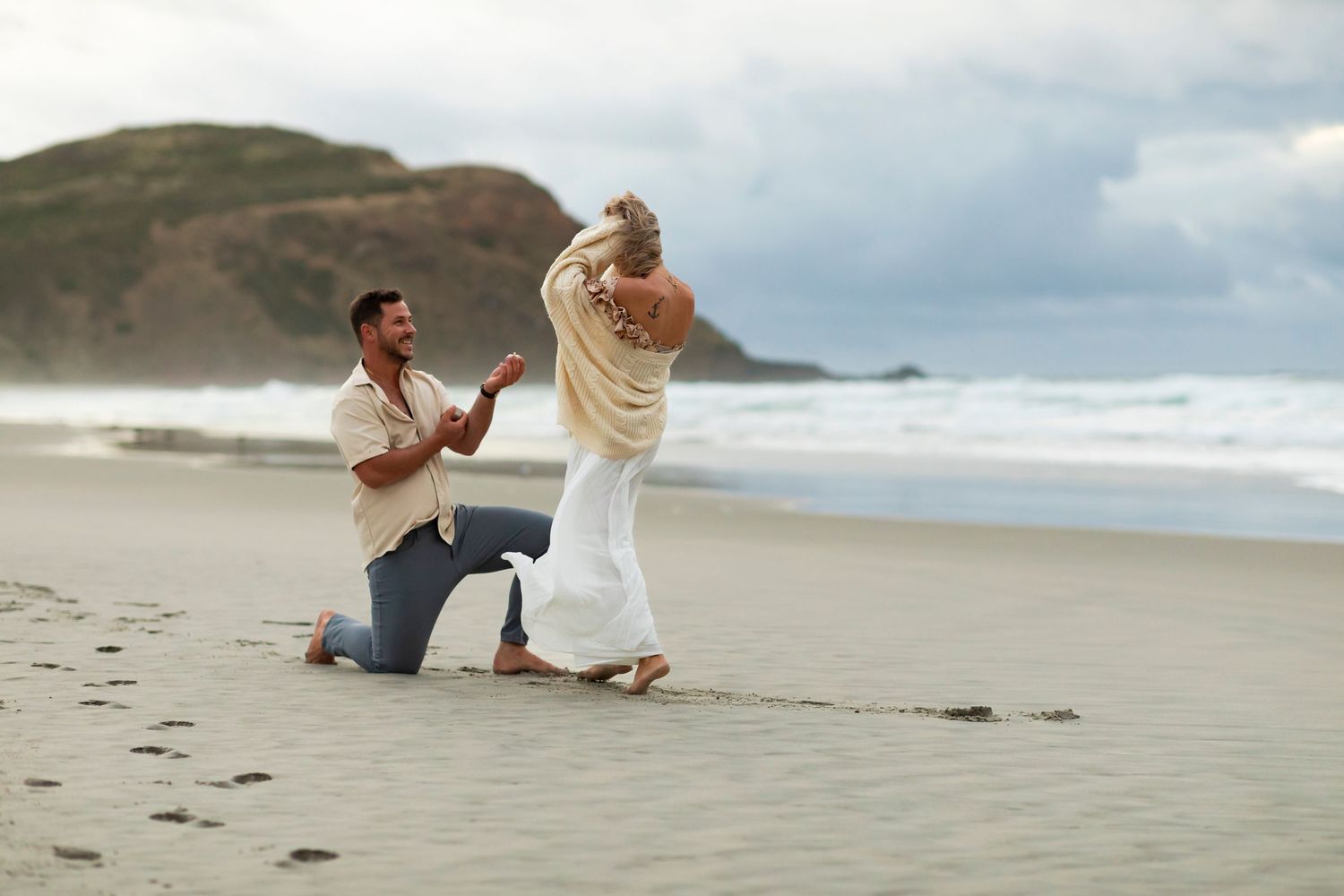 destination photoshoot of beach engagement new zealand man on one knee