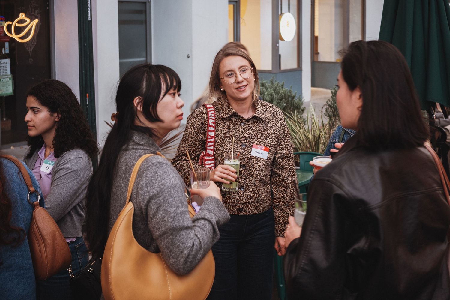 Women networking at a social event, smiling and conversing in a casual indoor setting.