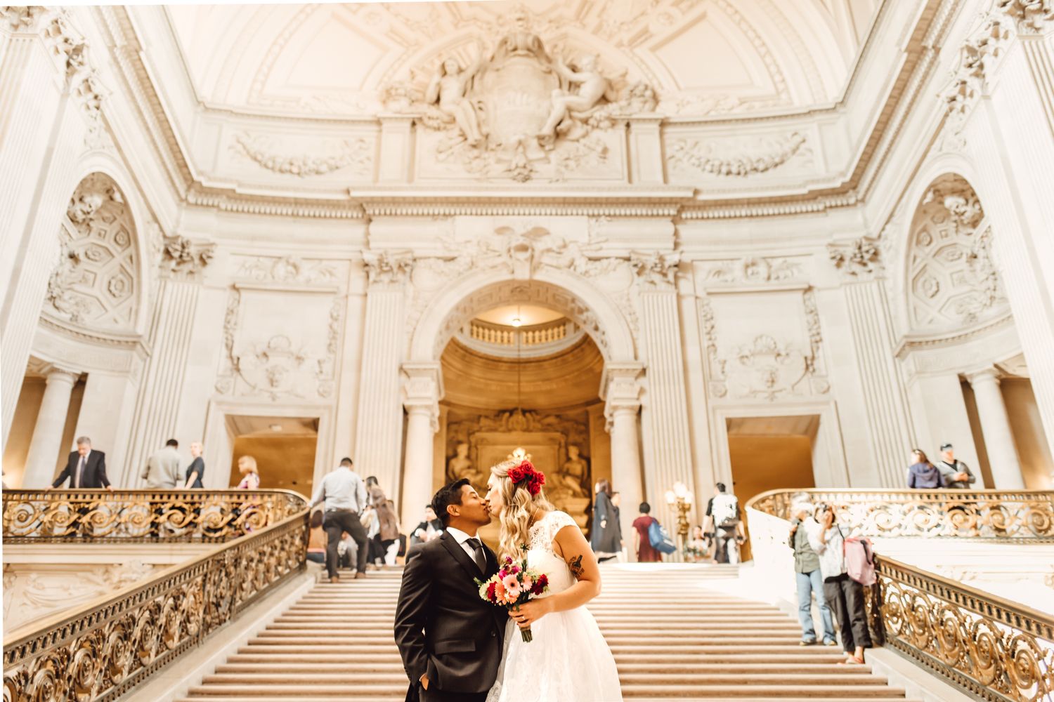 Bride and groom share a romantic kiss on the grand staircase of San Francisco City Hall.