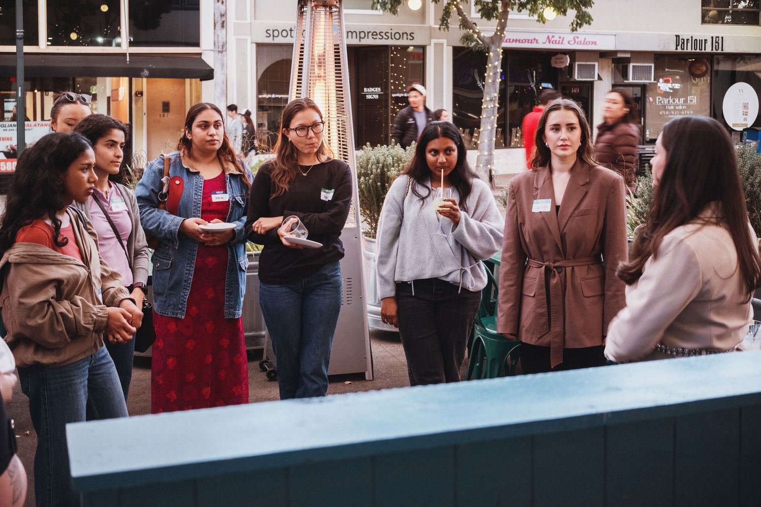 A diverse group of women networking outdoors at a professional event on a city street.