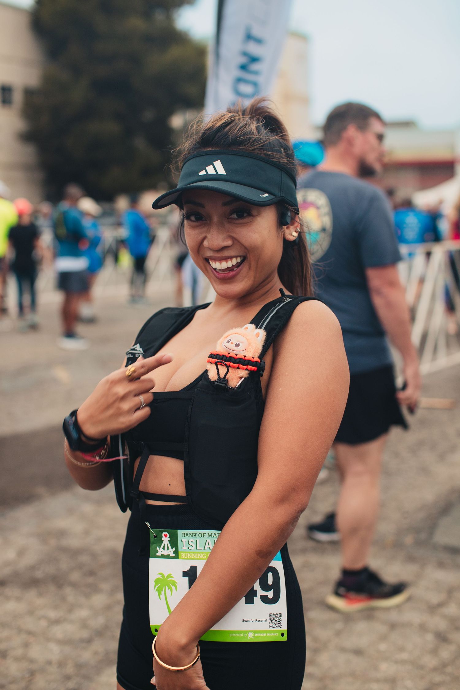 Smiling woman in black athletic wear and Adidas visor poses at a road race event with race bib number 19.