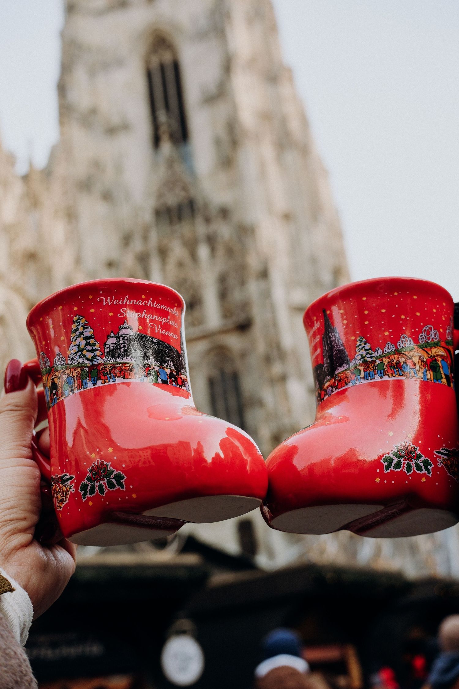 Two red traditional Dutch wooden clogs clink together in front of the Gothic spires of Milan Cathedral in Italy.