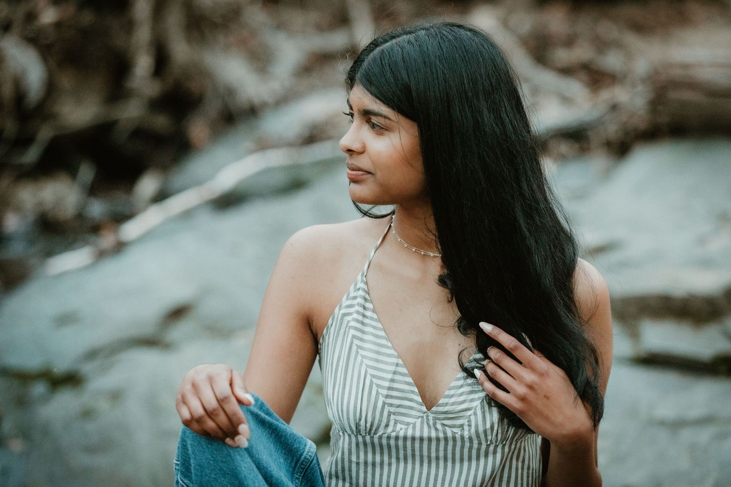 senior portrait of beautiful girl  in a creek against a rocky background.