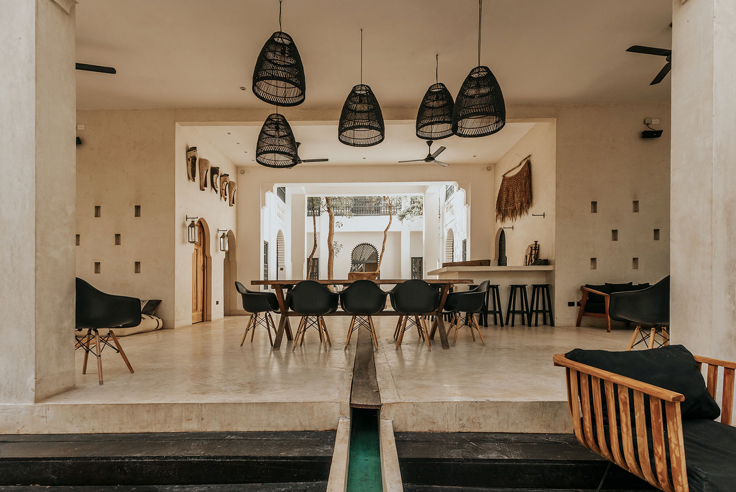 Modern restaurant interior with black pendant lights, sleek seating, and warm wood accents creates a minimalist dining space.