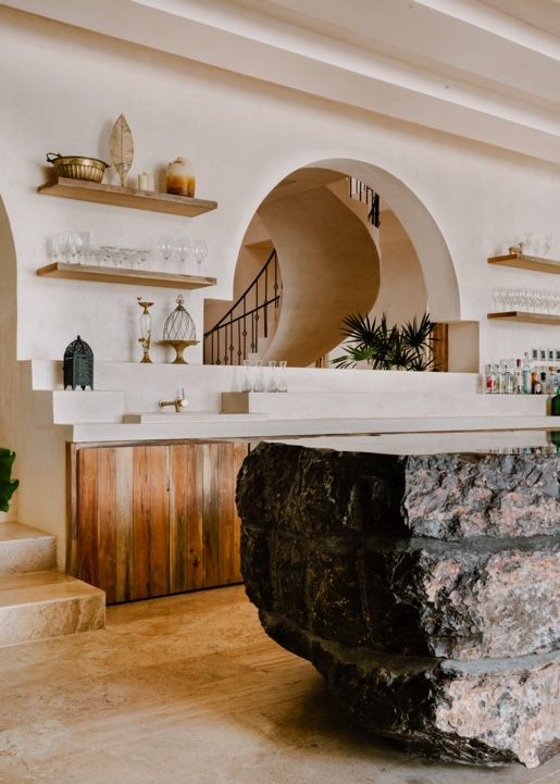Modern interior design featuring arched doorways, wooden cabinetry, and natural stone elements in an open concept space.