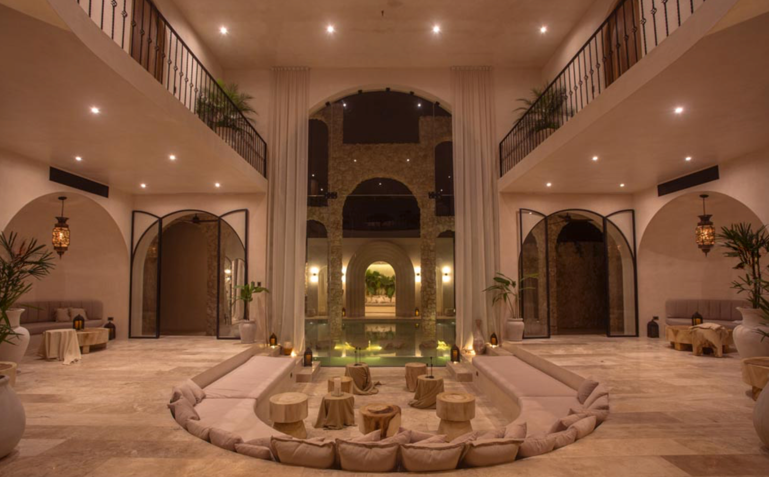 Elegant curved staircase with wrought iron railings and recessed lighting in a luxurious Mediterranean-style foyer.