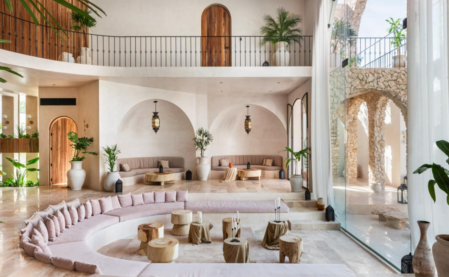 Bright Mediterranean-style interior with arched doorways, white walls, curved seating, and tropical plants throughout.