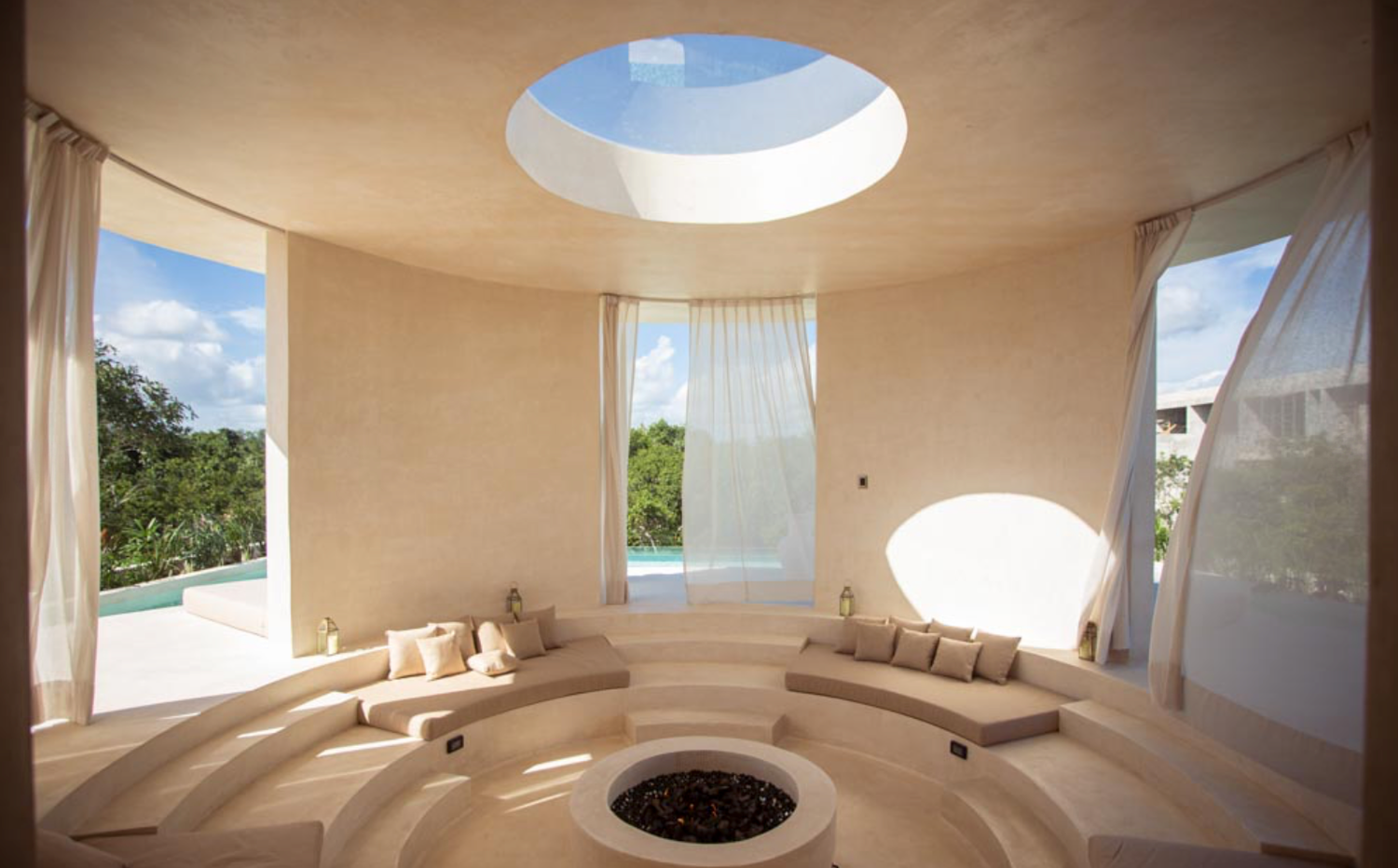 Modern white curved seating area with circular skylight and minimalist interior design features in a contemporary space.