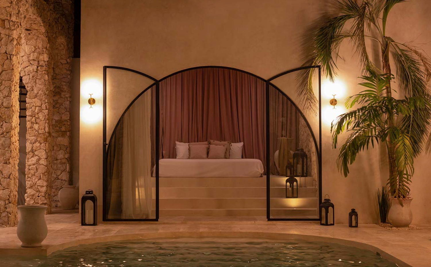 Elegant hallway with arched doorways, sconce lighting, potted plants and stone walls creating a luxurious ambiance.