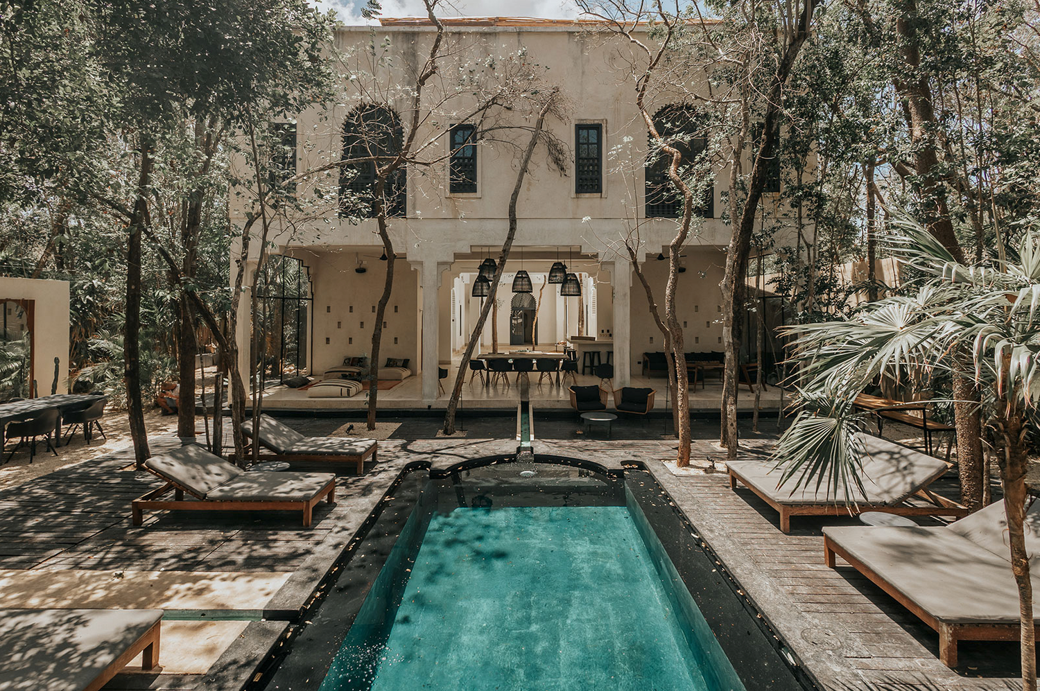 A tranquil desert resort setting features a turquoise swimming pool surrounded by desert landscaping and modern architecture.