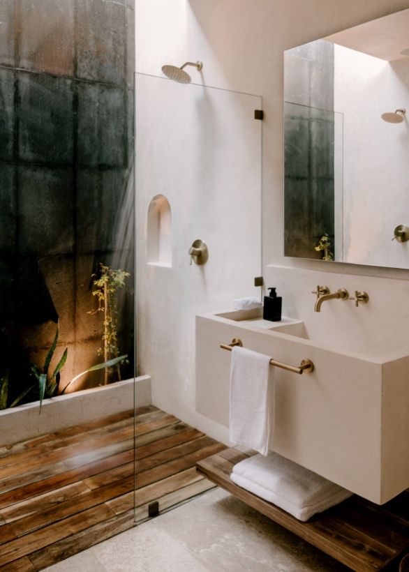Modern bathroom features floating white sink and rustic wood flooring with sleek glass shower enclosure.