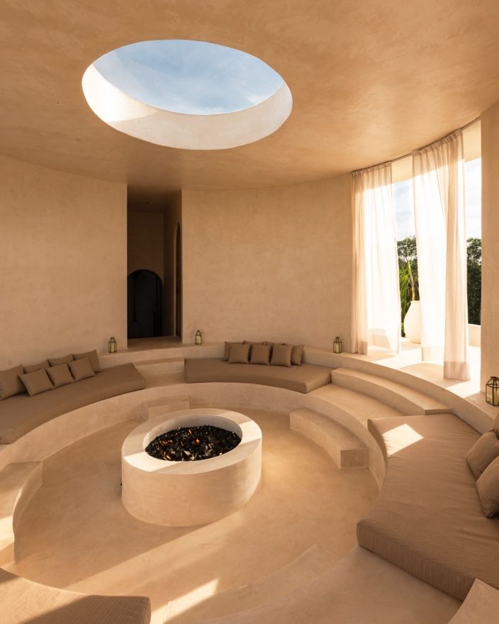 Modern circular room with built-in seating and skylights creating a serene atmosphere with natural light and curved walls.