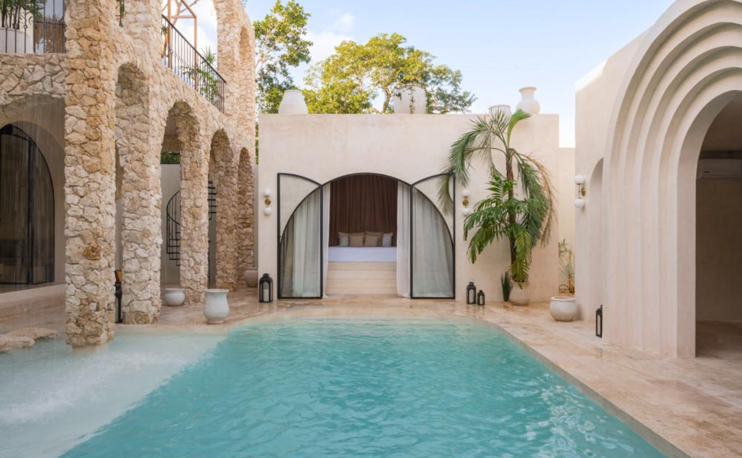 Luxurious Mediterranean villa courtyard features a sleek lap pool surrounded by stone archways and white walls.