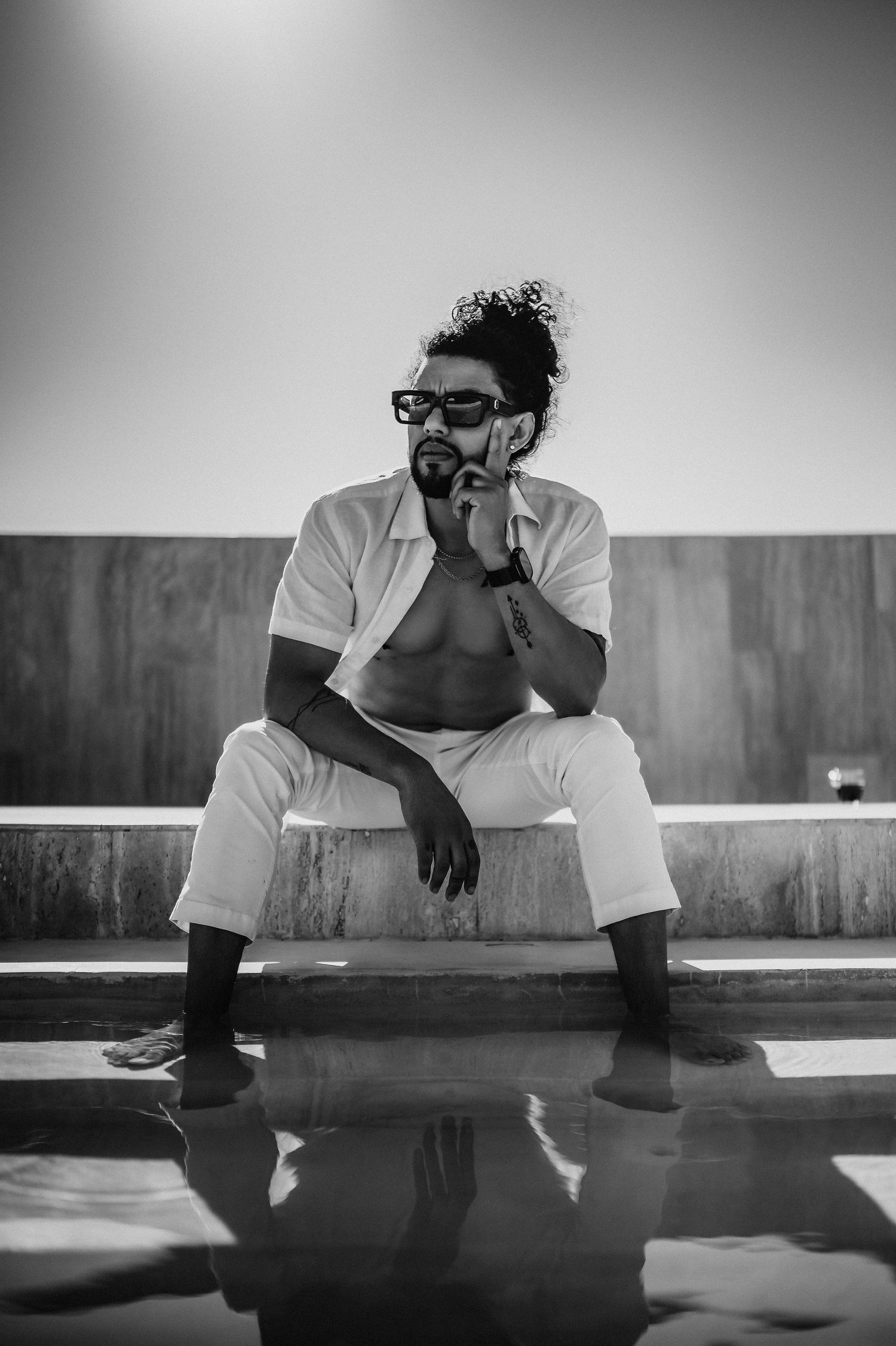 A series of black and white photos showing someone in a white t-shirt sitting and reflecting on a reflective surface.