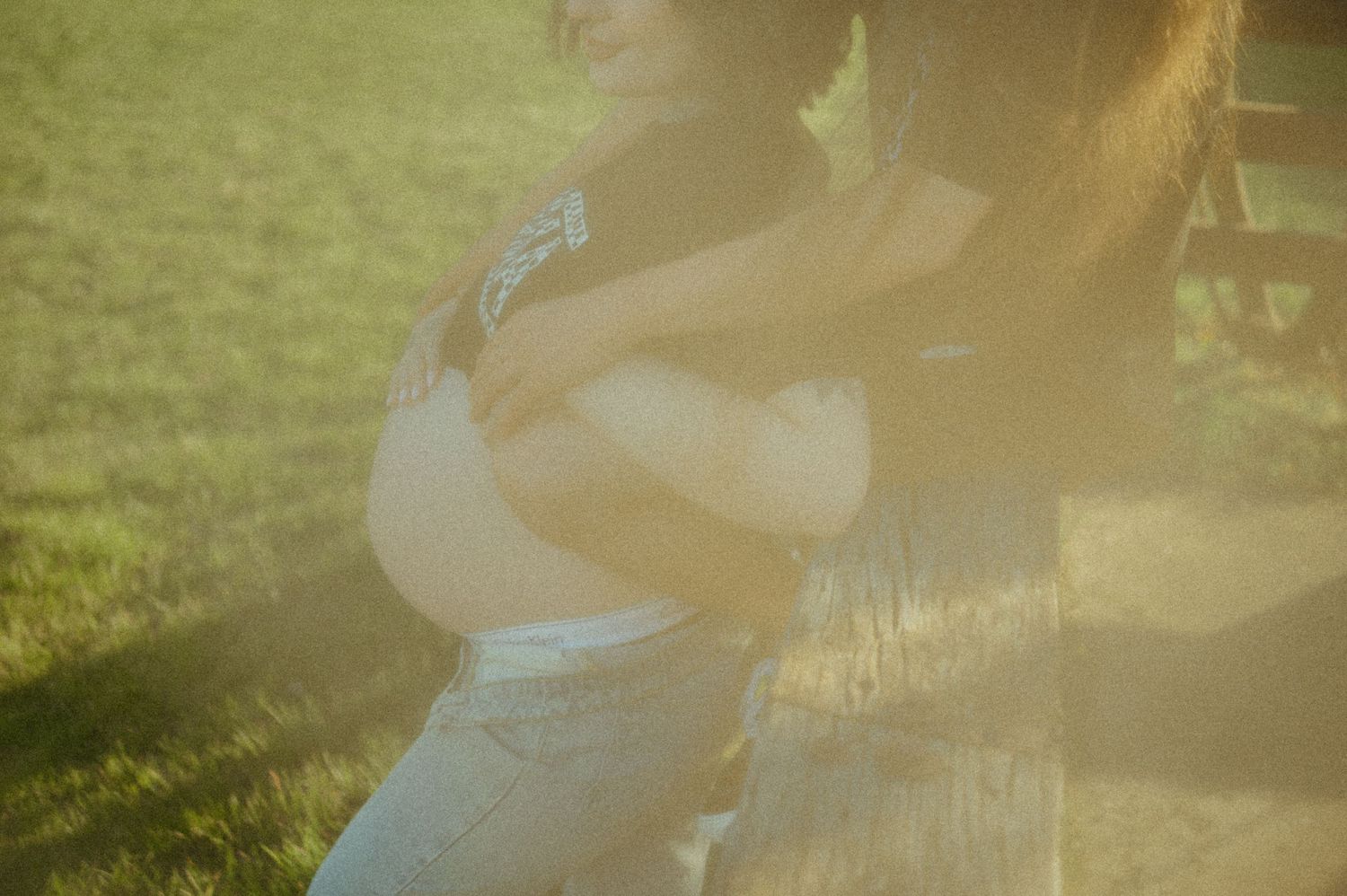 Dreamy soft focus shot of a person in a white sundress standing in sunlit grass with lens flare effects.