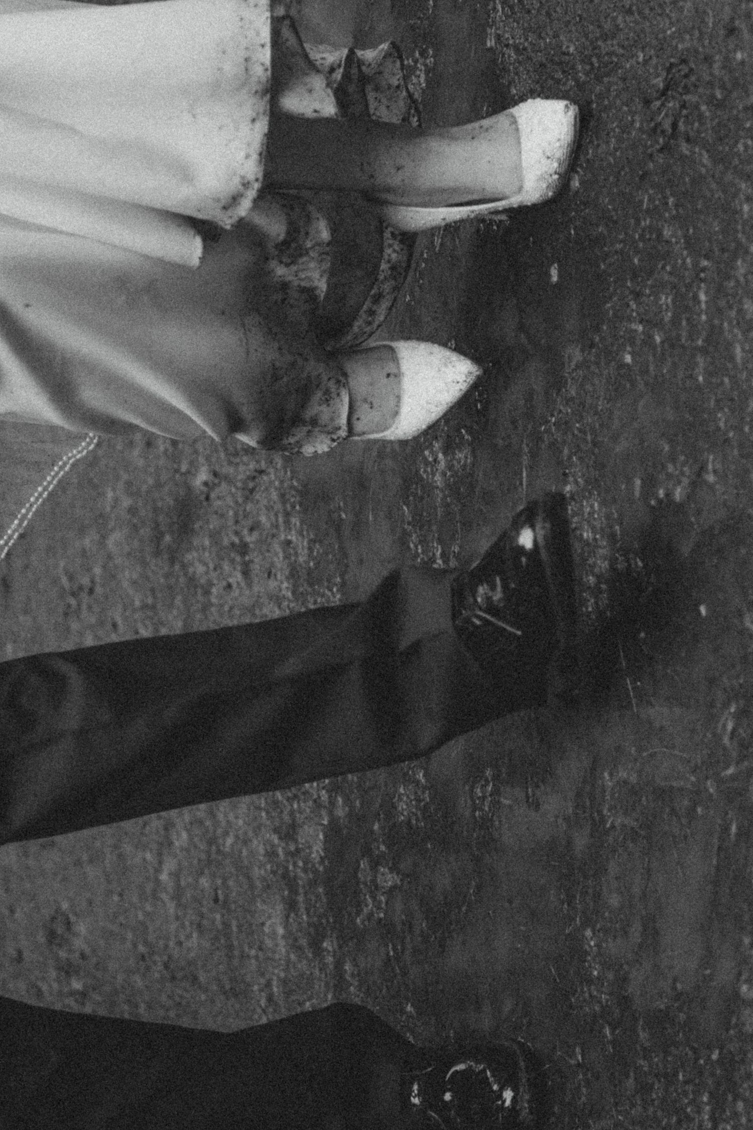 Black and white vintage photograph showing legs wearing light colored stockings and heels against a dark floor.