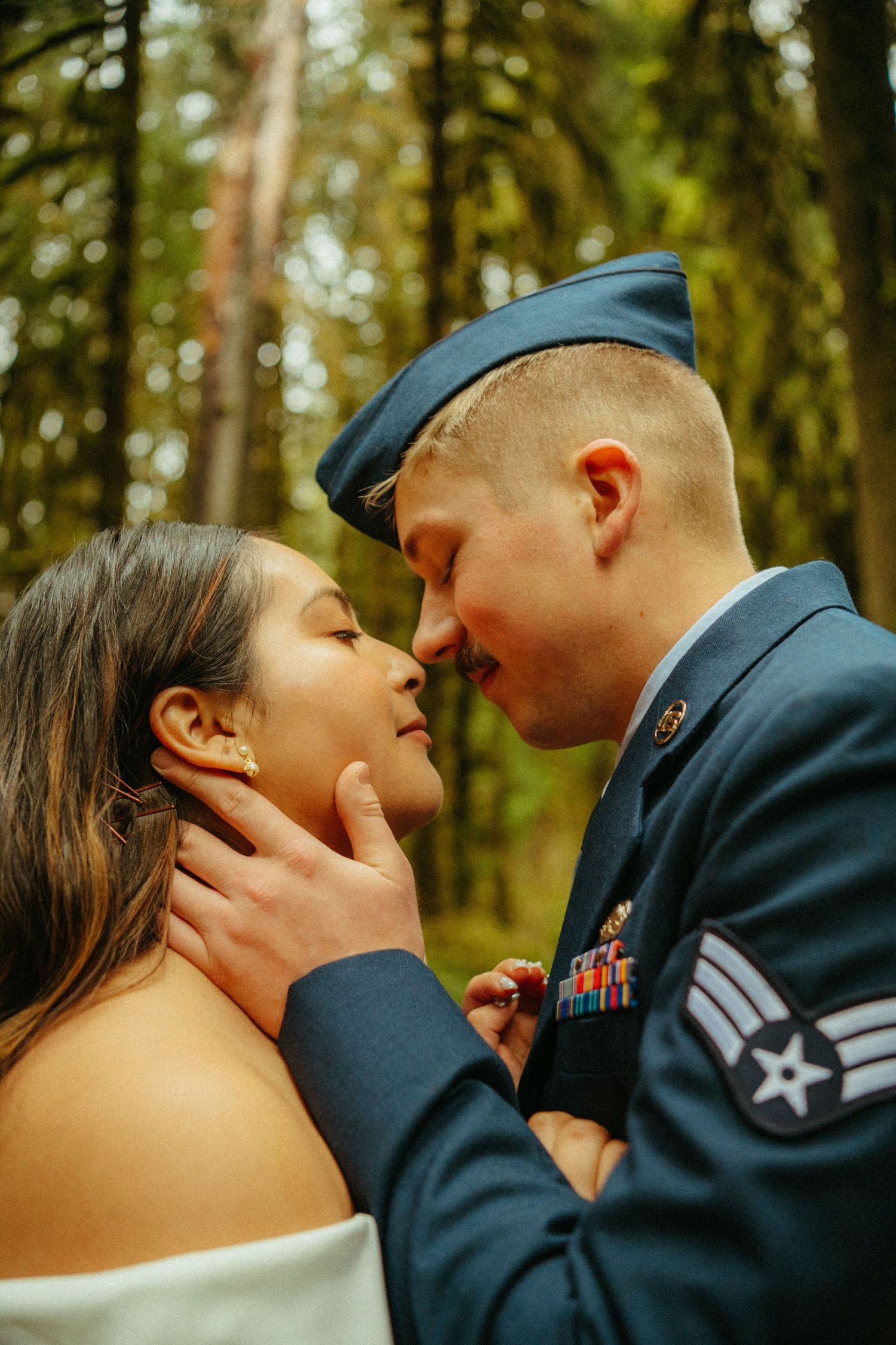A romantic outdoor portrait captured in a forest with sunlit trees creating a dreamy natural backdrop.