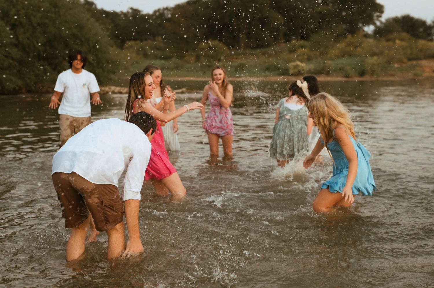People playing and splashing together in shallow water at sunset creating a fun summer scene.