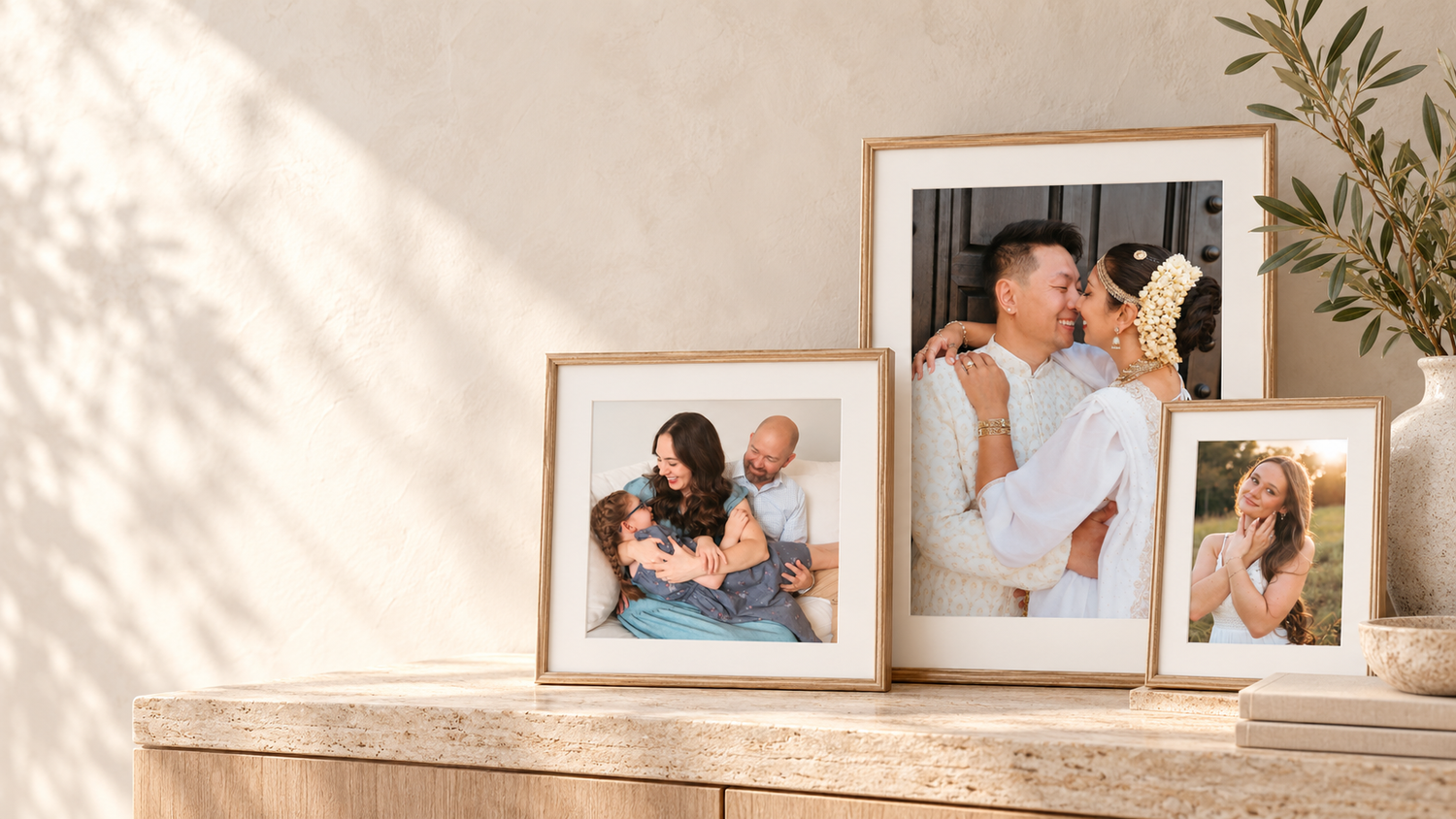 Three gold-framed family photos displayed on a wooden shelf, featuring joyful family portraits in warm, natural light.