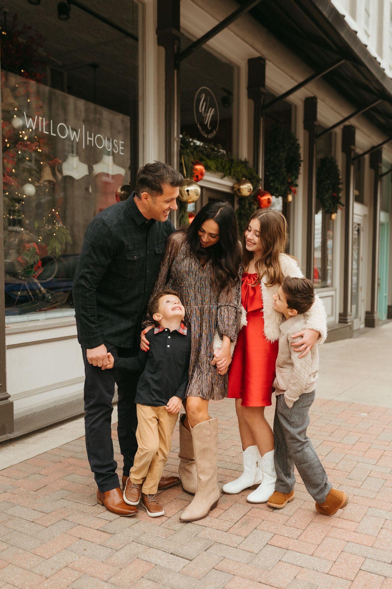 Family of five smiling together outside Willow House store decorated for Christmas holidays.