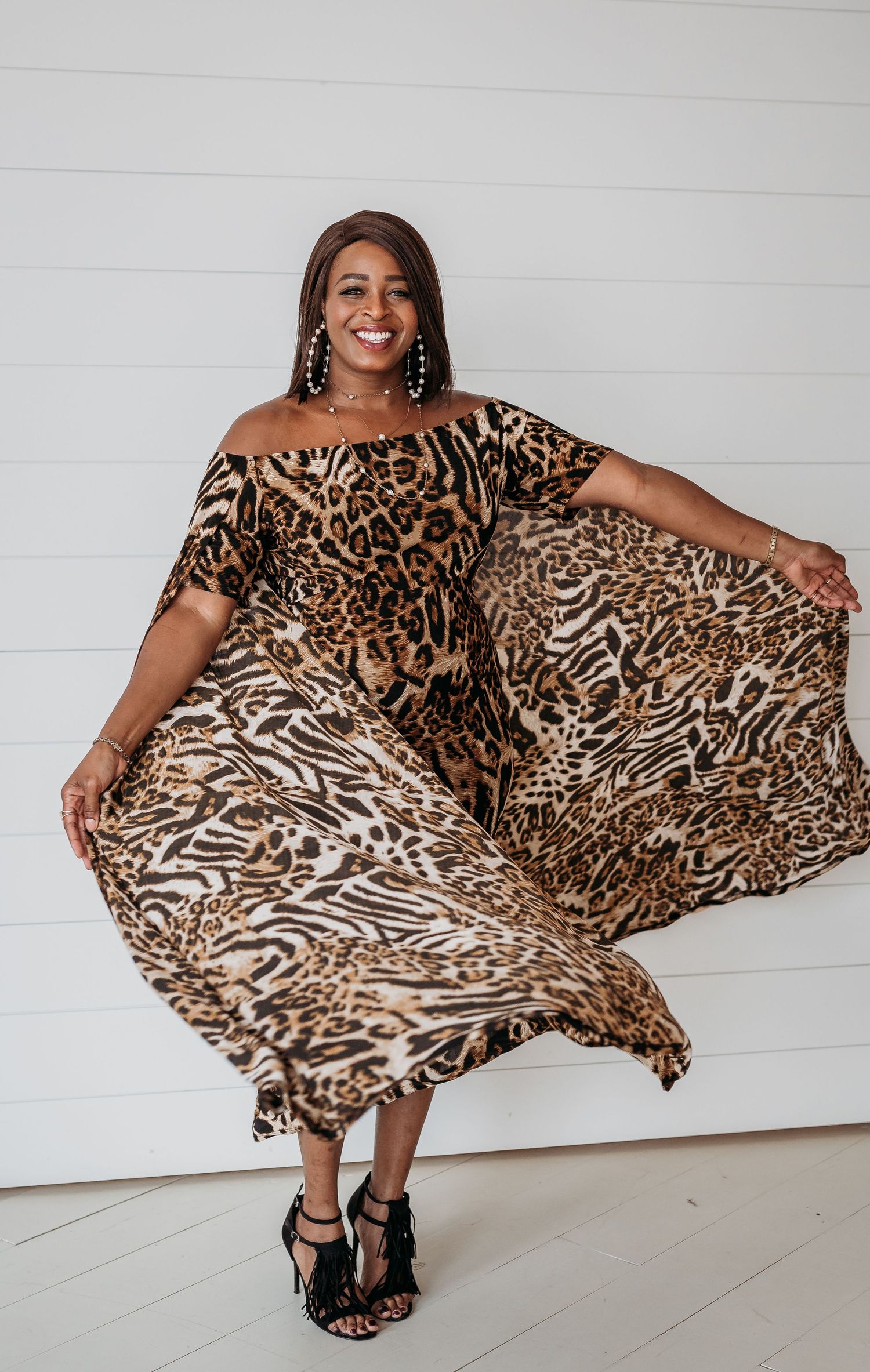 A flowing leopard print dress moves dynamically in a series of poses against a white wall.